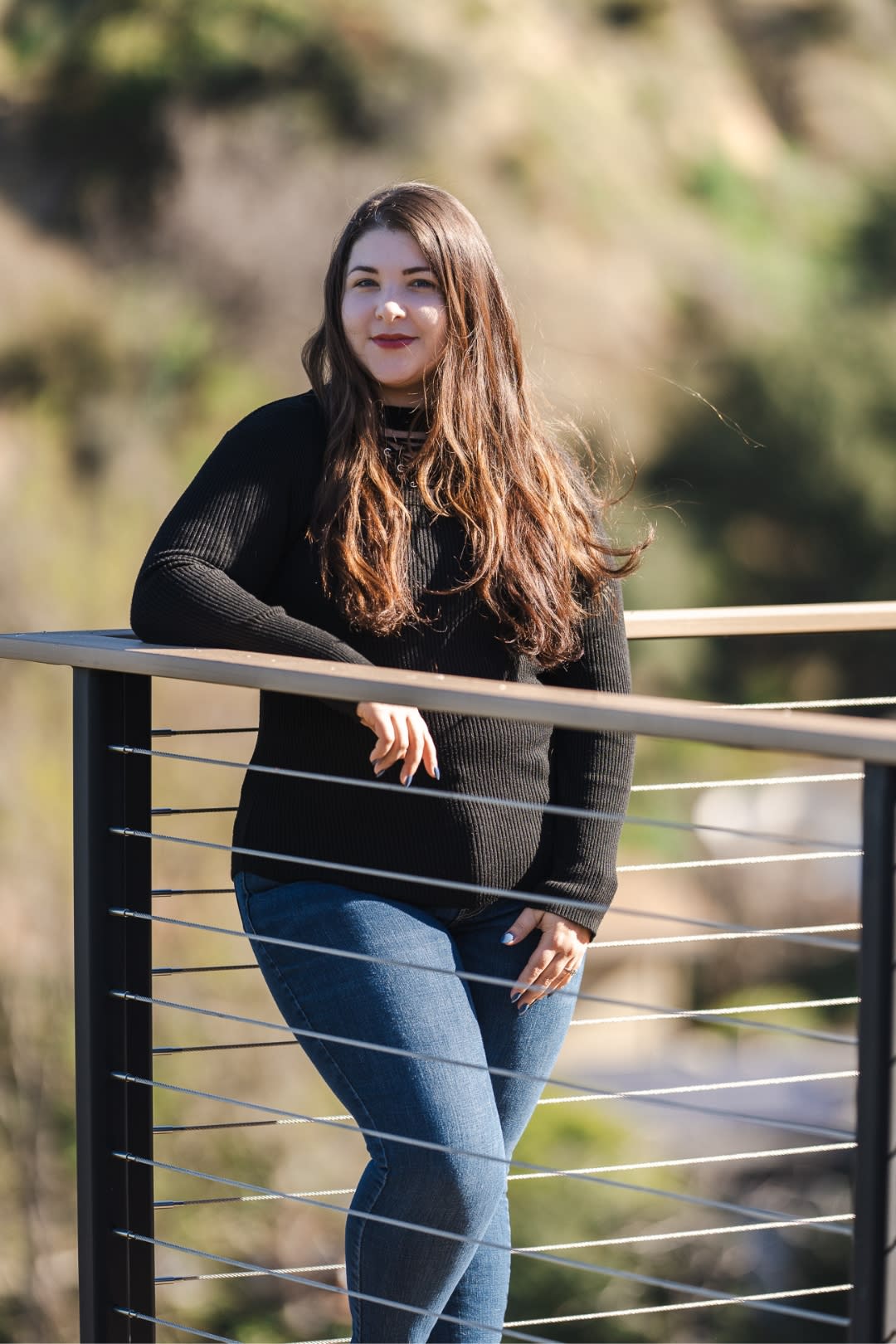 woman in brown sweater standing outside on a deck