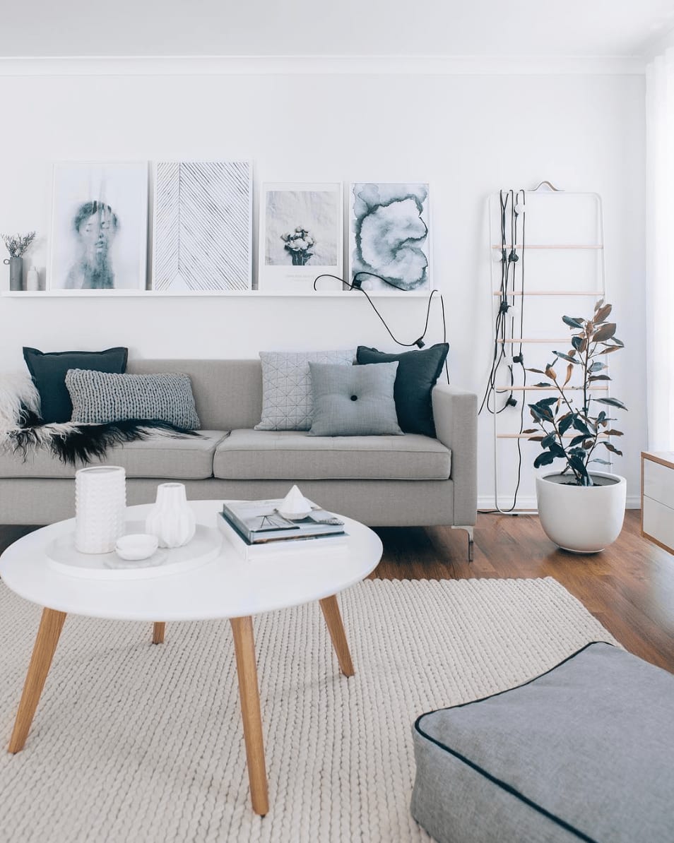 Contemporary living room with a gray sofa, abstract art, round coffee table, and large woven rug.