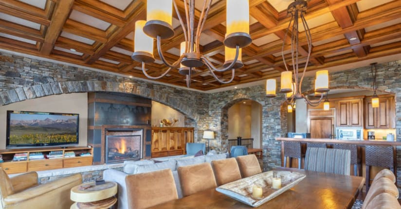 Luxury living room with stone fireplace, wooden coffered ceiling, and rustic decor in Telluride home.