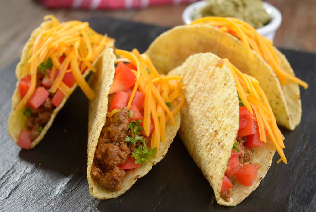 Tacos with ground beef, cheese, vegetables, and guacamole sauce