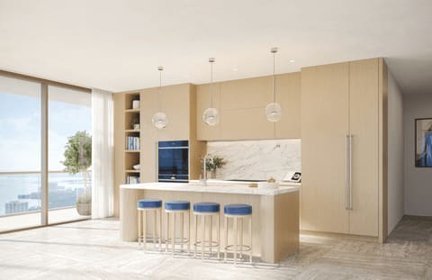 Modern condo kitchen with a marble island, blue stools, and floor-to-ceiling windows overlooking water.