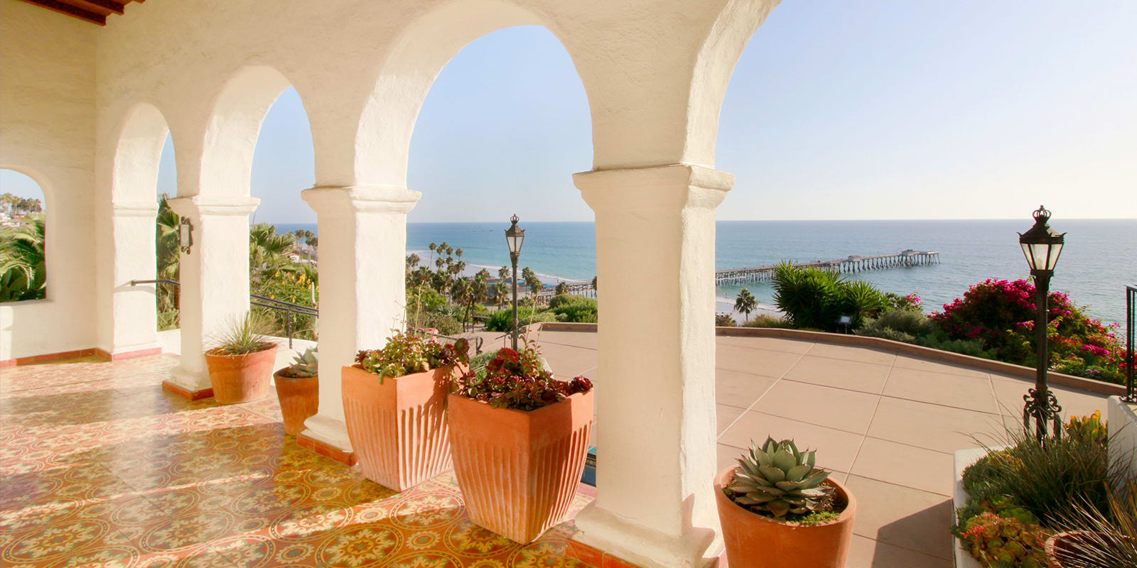 View of the ocean and pier from Casa Romantica, a building with white arches