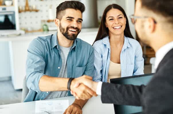 Real estate agent with couple shaking hands closing a deal and signing a contract