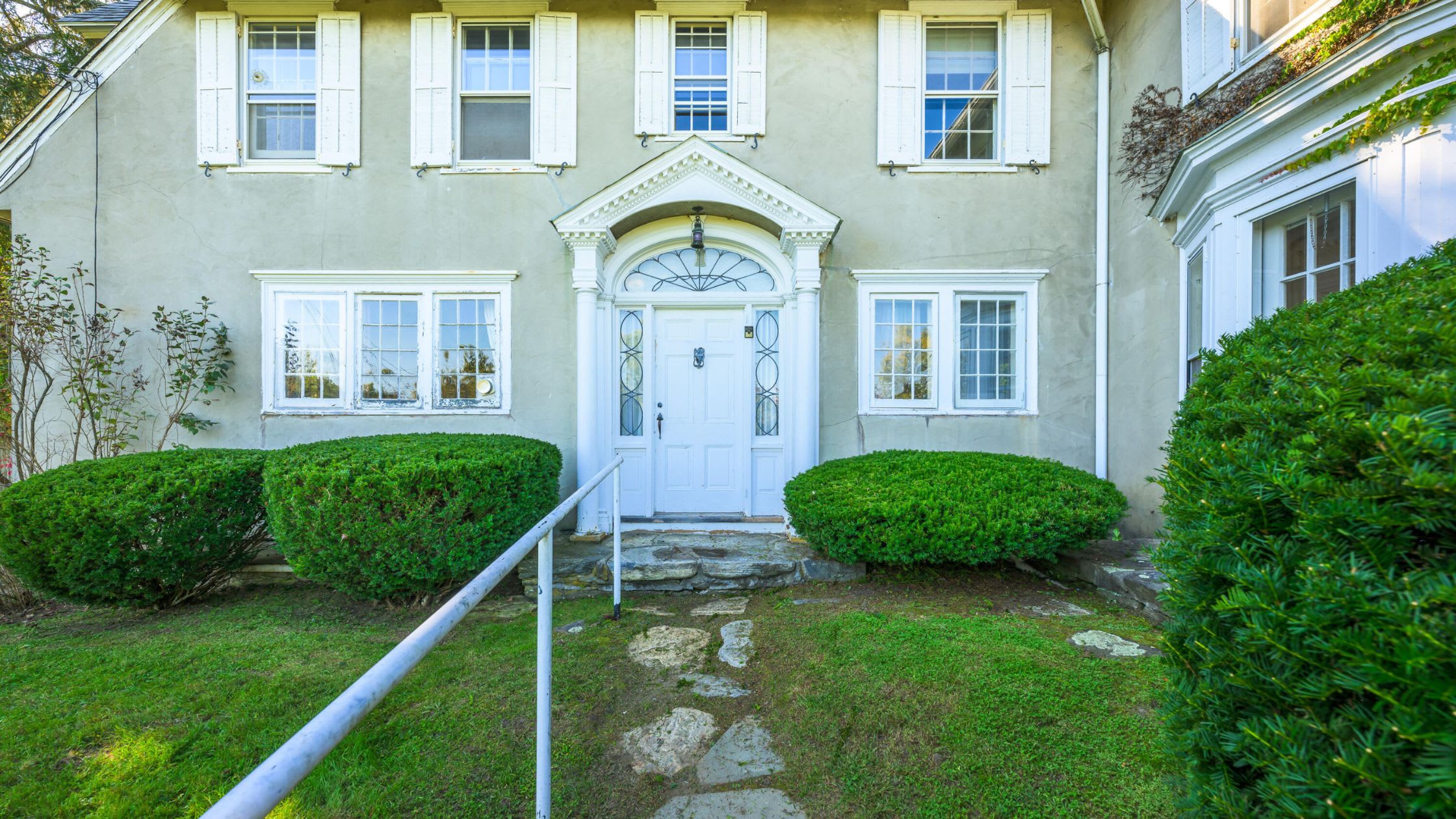 view of the front of the front door with a large peak above the door and large white framing around the white front door. - 2 Cherry St Stockbridge, MA 01262