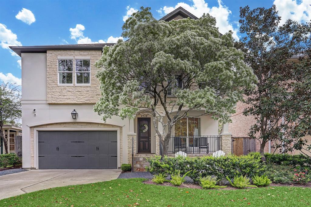 A single-story ranch-style house with black railings, a front lawn, and a paved driveway leading up to a two-car garage. 