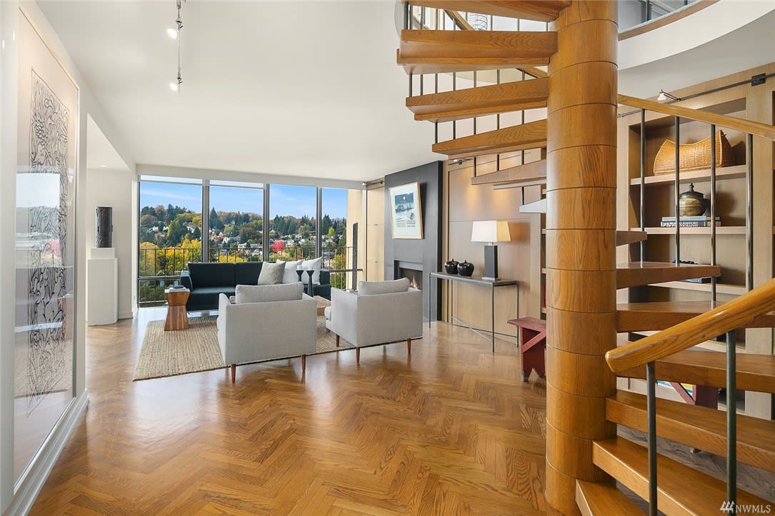 Spacious condo living area with herringbone wood flooring, modern furniture, and abundant natural light.