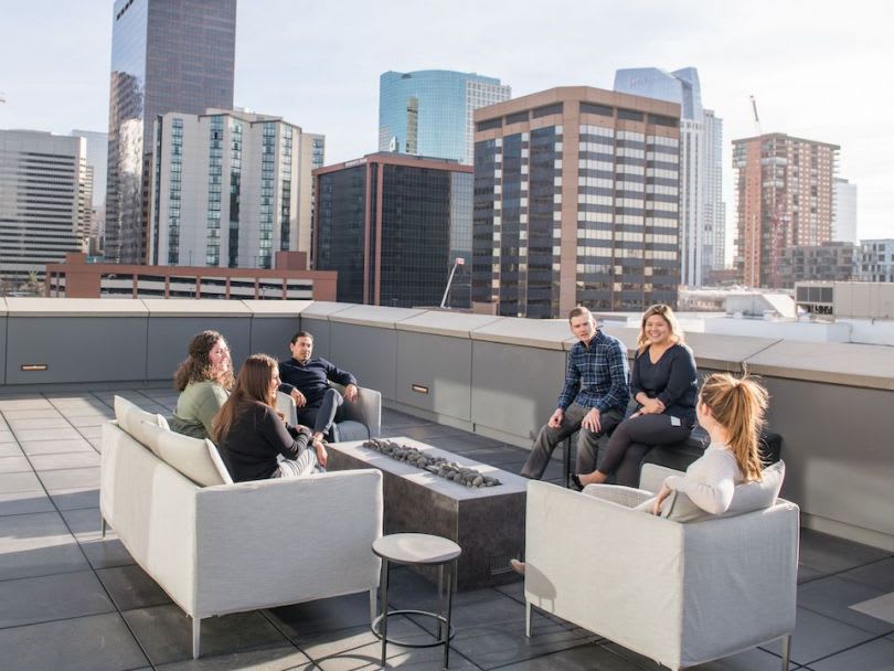 Five people gather on a rooftop terrace with downtown high-rises behind them.