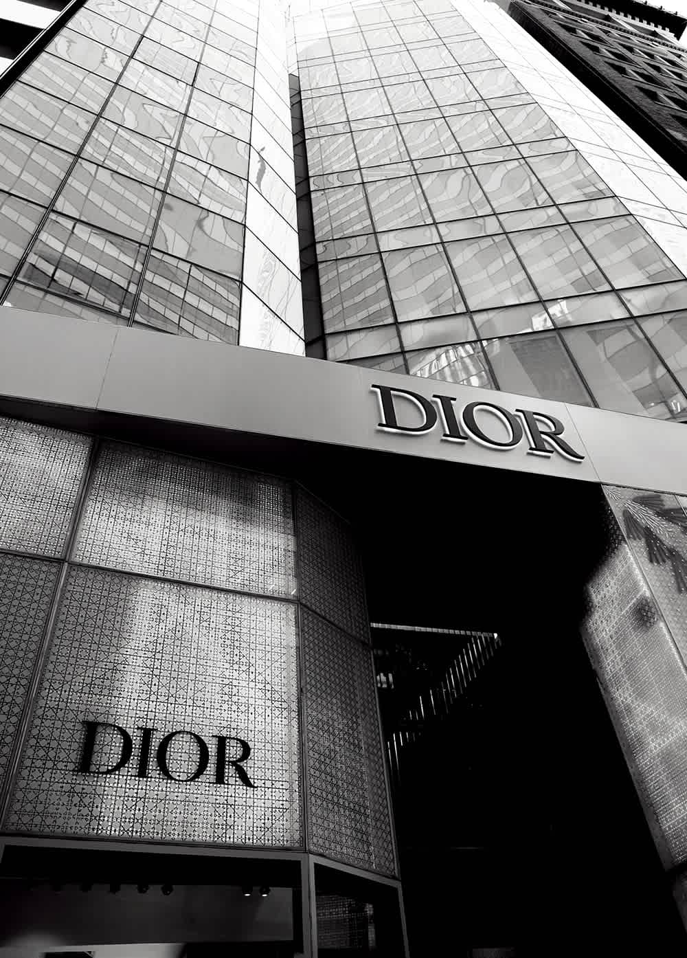 A modern building facade featuring the "Dior" logo, with reflective glass and intricate patterns in black and white.