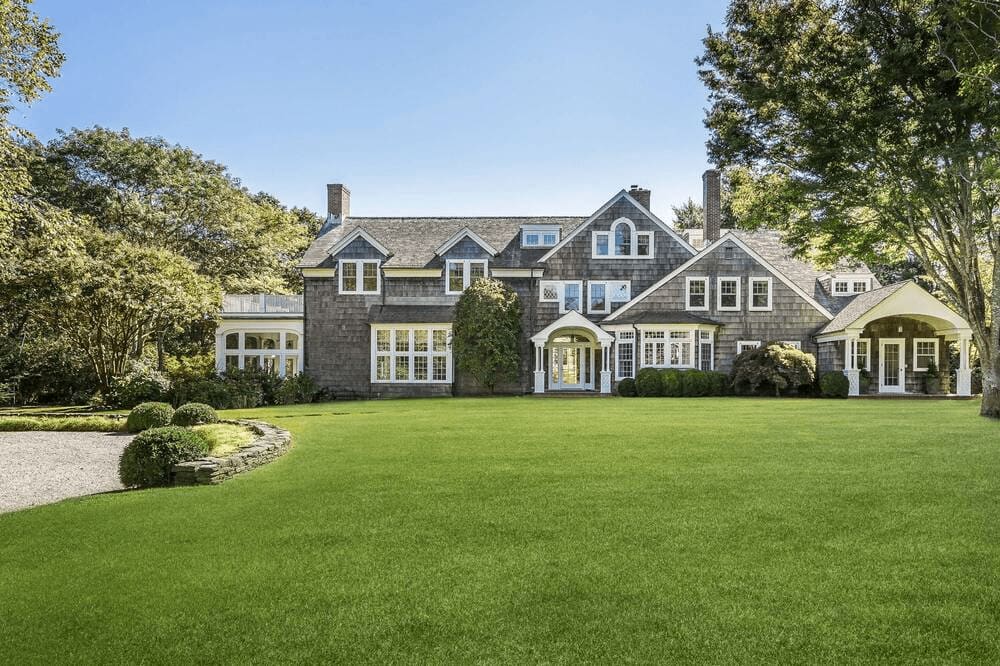 A spacious colonial house with a manicured lawn and mature trees