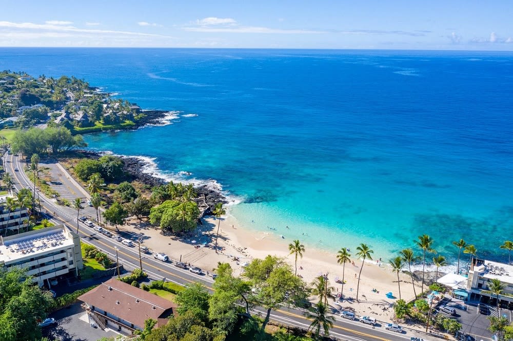 aerial view of Kailua-Kona beach, with cars, people, and buildings surrounding it