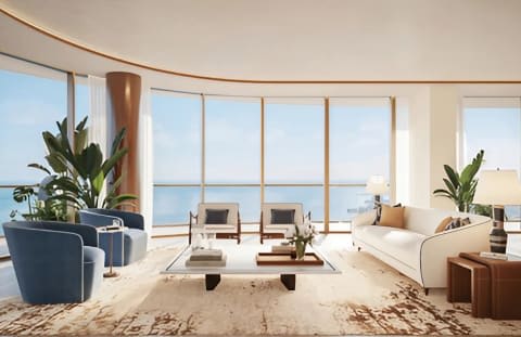 Living room with curved ocean-facing windows, a white sofa, and blue lounge chairs.