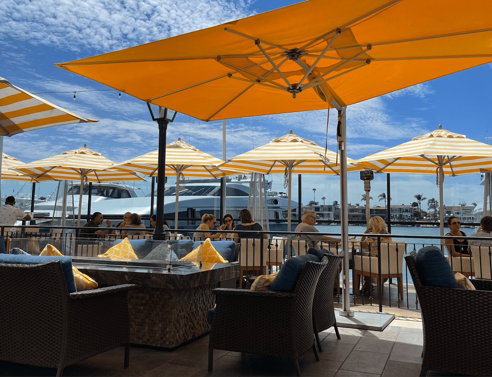 Outdoor dining area with yellow-striped umbrellas at a waterfront restaurant.