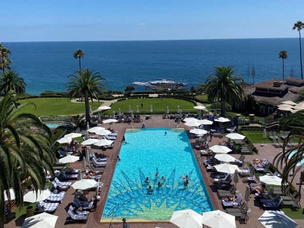 Oceanfront resort with a large pool, palm trees, and sun loungers overlooking the ocean.