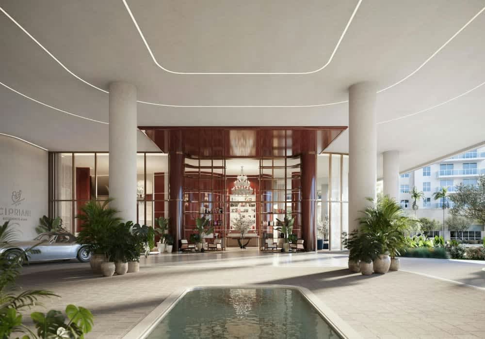 Cipriani Residences entrance lobby with a reflecting pool, potted palms, and a silver car.