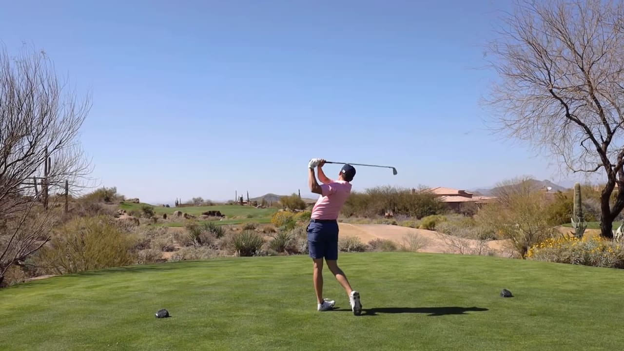 A golfer swings a club on a lush green field, exuding a serene atmosphere.