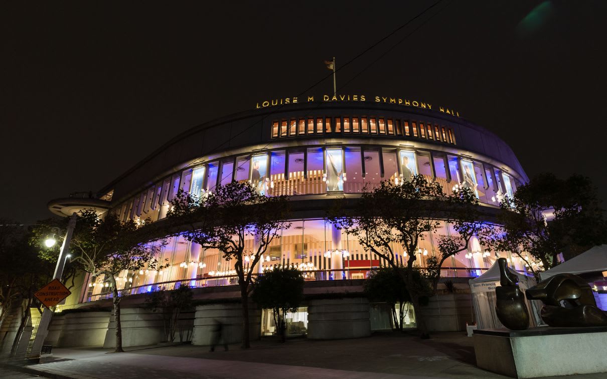 The Louise M. Davies Symphony Hall glows against the San Francisco night sky. This impressive building is home to the San Francisco Symphony Orchestra, one of the oldest and acclaimed orchestras in the United States. Designed by architect Louis M. Davies, the hall opened in 1972 and is known for its beautiful architecture and acoustics.