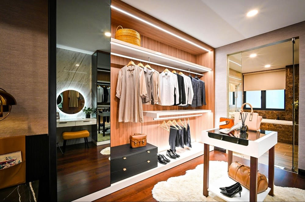 A walk-in closet with well-organized clothes that are neatly hung, and a large and well-lit mirror.