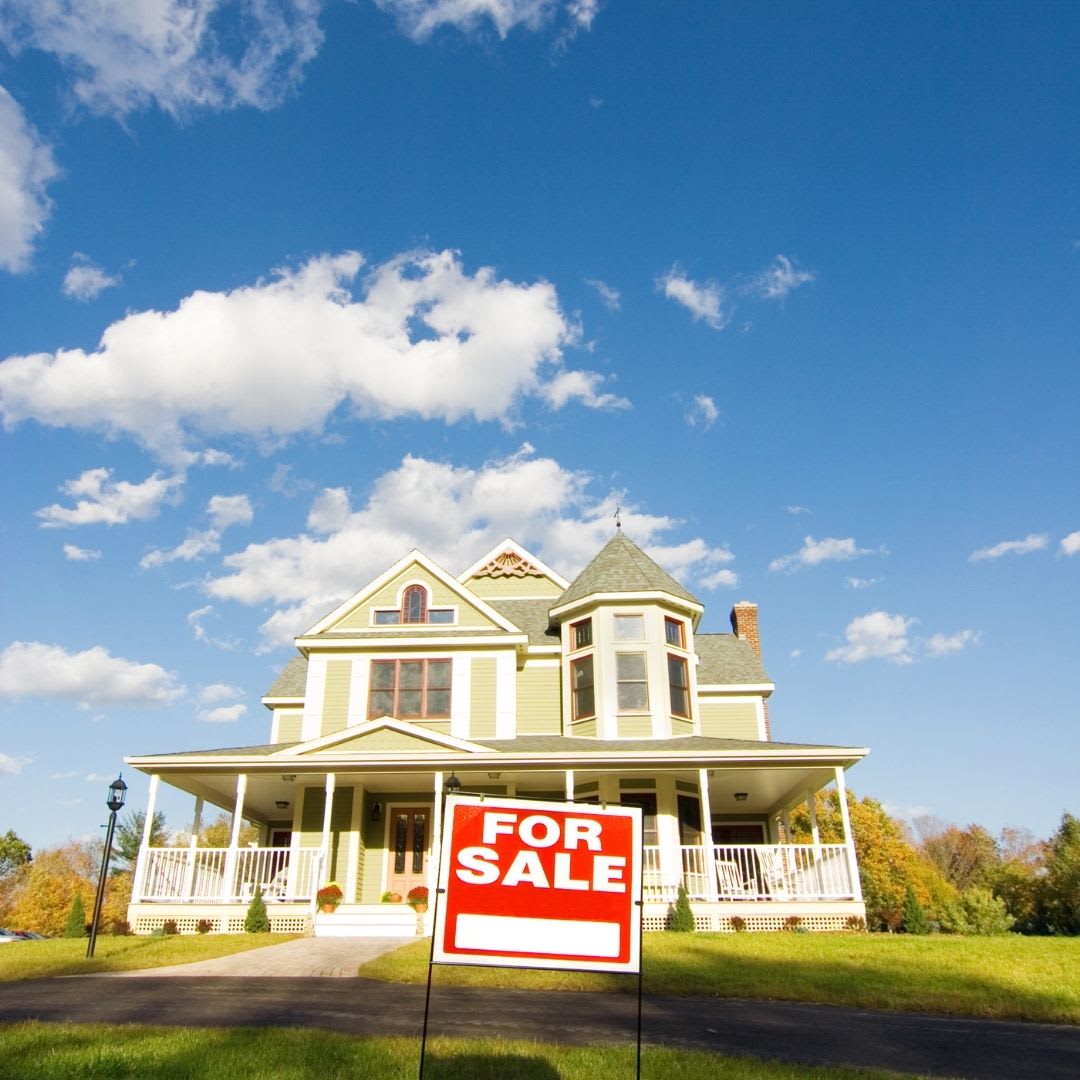 a large white home with a red for sale sign