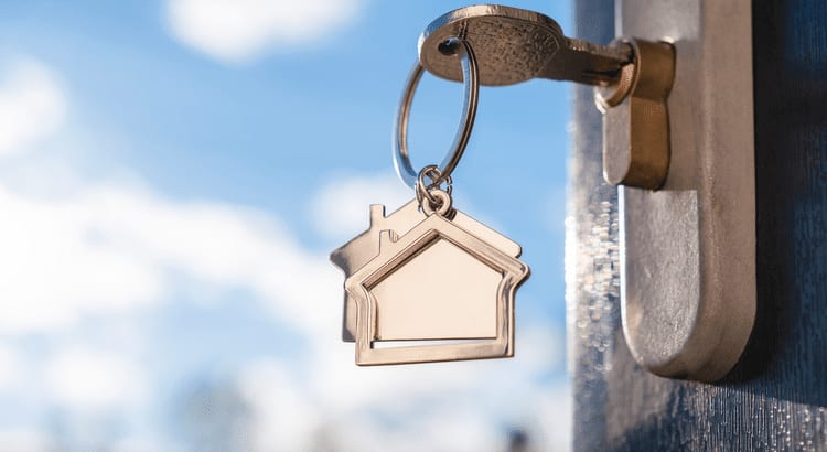 Photo of key in home door keyhole with home shaped keyring