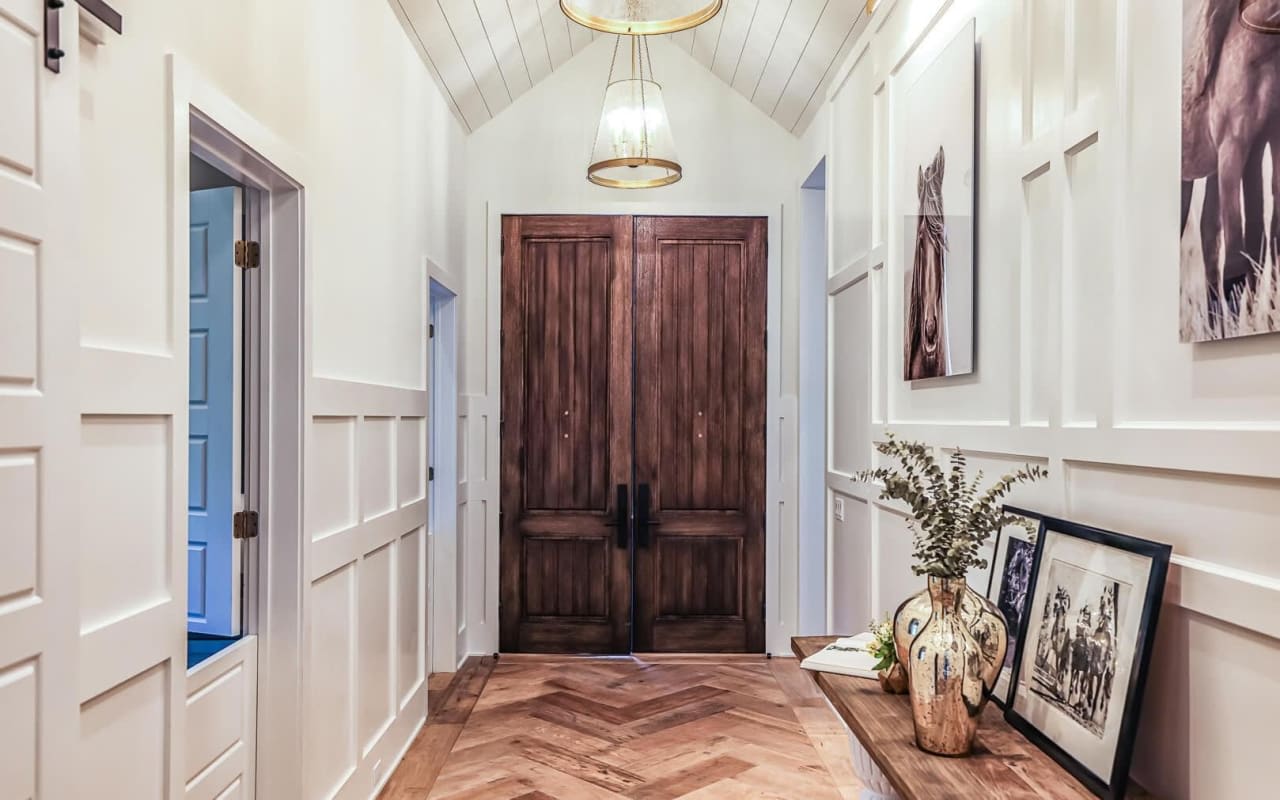 A welcoming doorway in an inviting home opens to a hallway with a wooden floor and a wooden door.