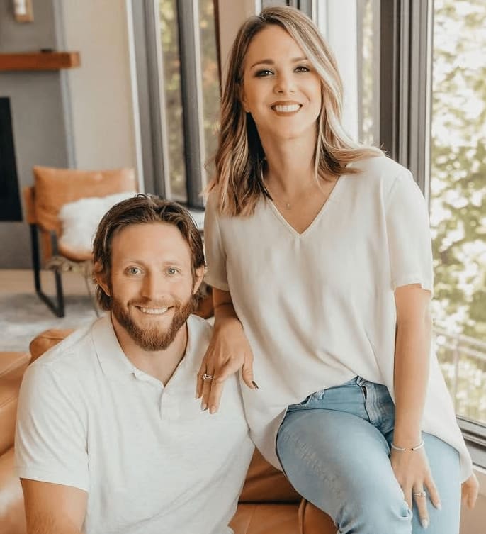 Chrissy and Brock Wood pose together in a bright living room.