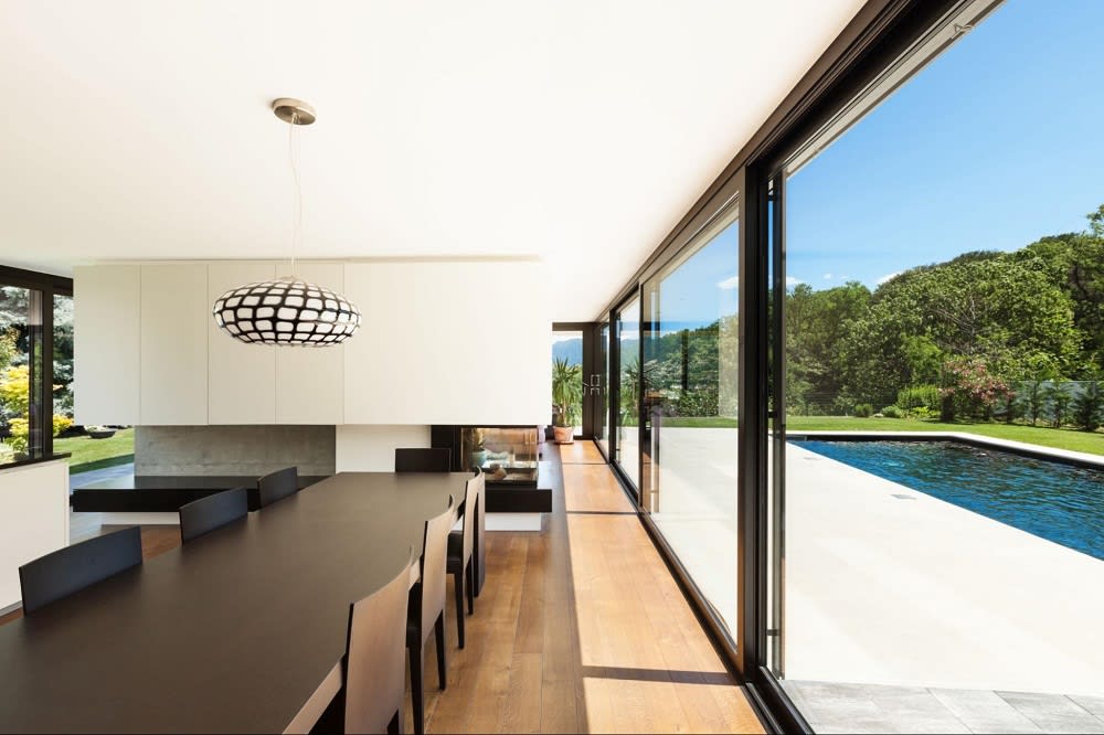 Black Long Table with Chairs and a Glass Door with a Pool Outside