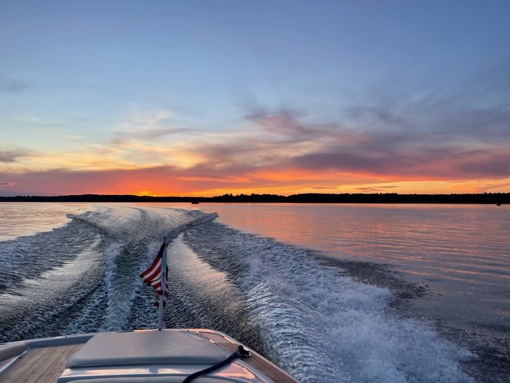 The sky is ablaze with orange, pink, and purple hues, reflected in the still water.