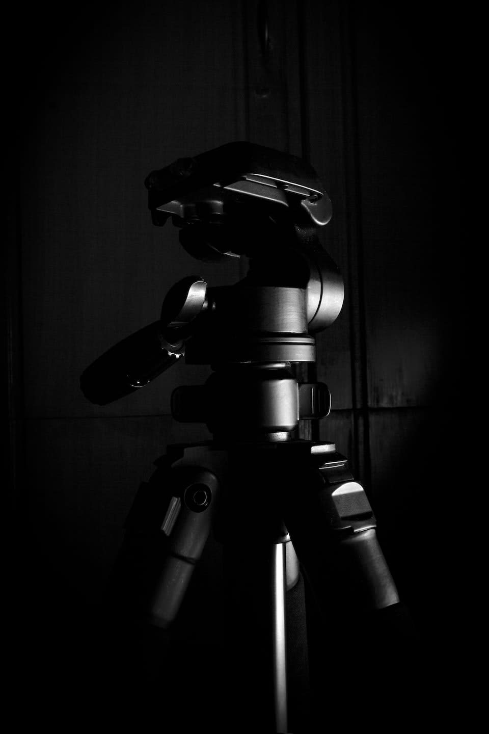 A black and white photo with a tripod with a camera attached to it.