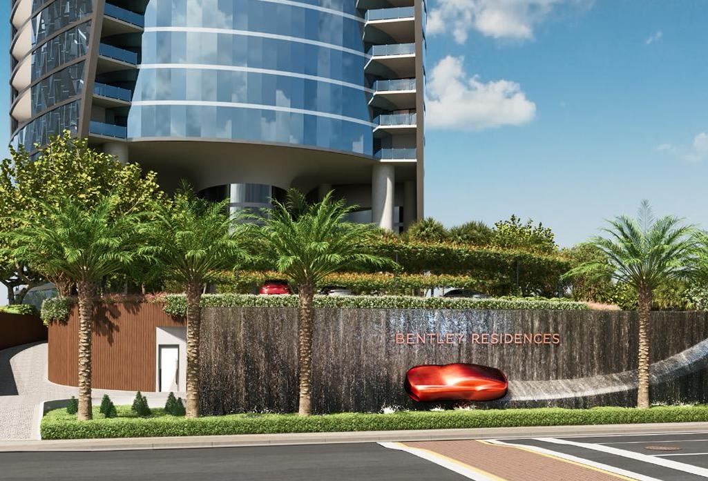 Bentley Residences tower with curved glass balconies and a landscaped entrance featuring a waterfall wall.