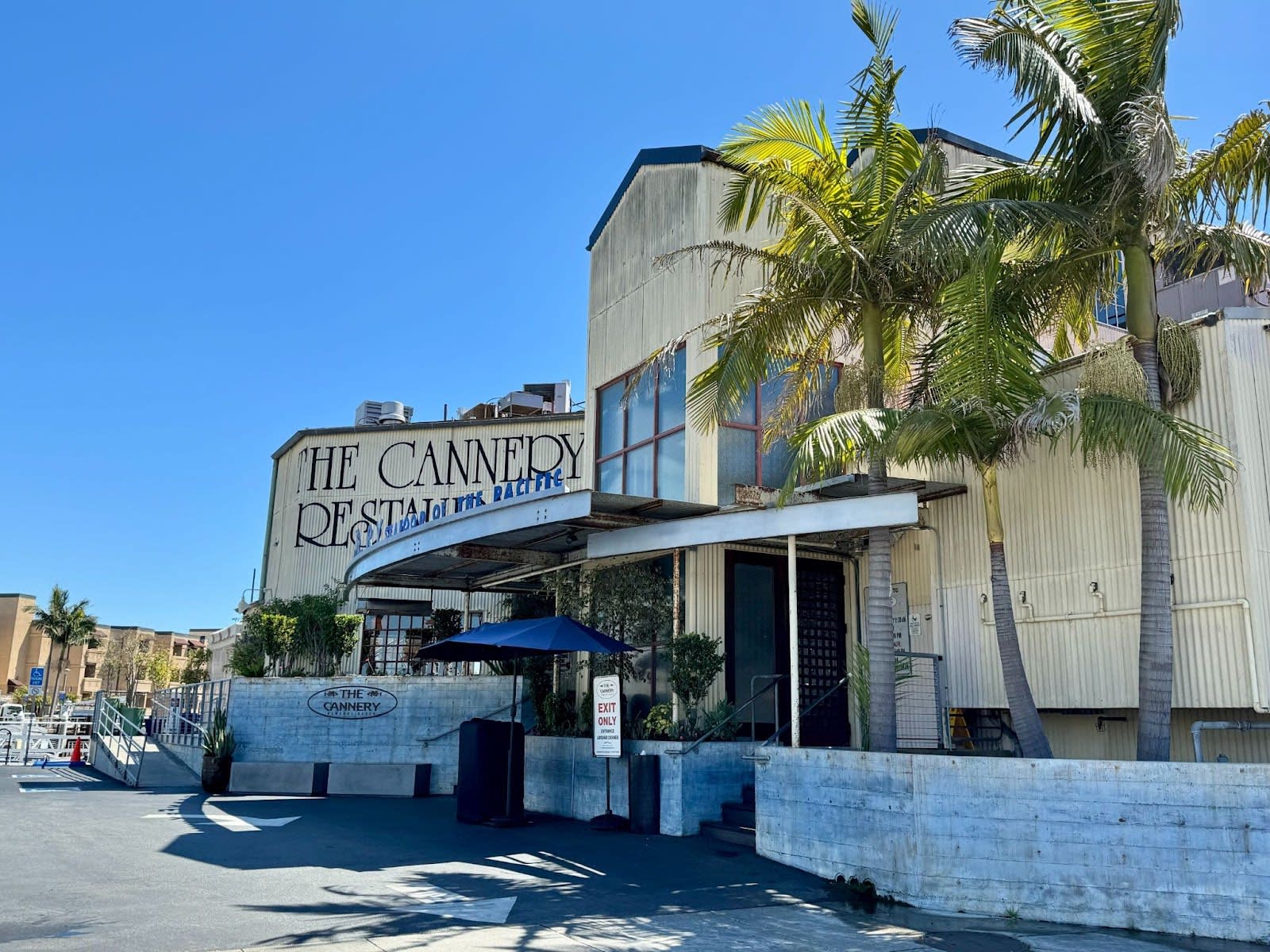 The Cannery restaurant exterior in Newport Beach, featuring a large sign and palm trees.