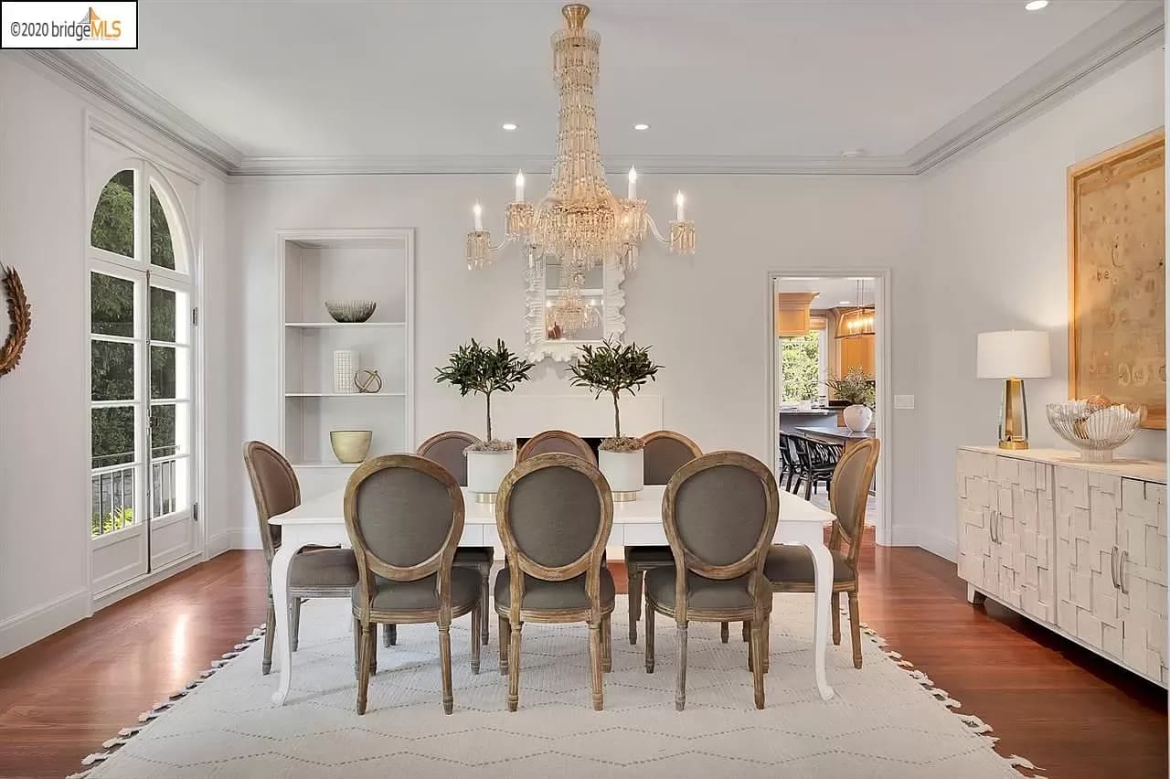 Simple but elegant minimalist designed dining room with a chandelier and 8 chairs dining table and white wall and light aesthetic