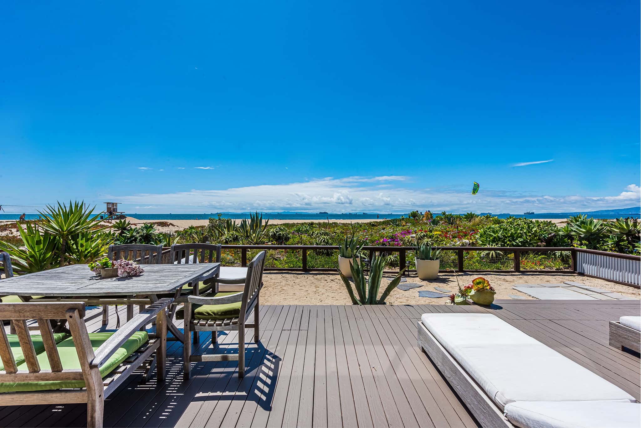 Outdoor deck looking out at ocean views and lush landscaping of natural California succulents and plants