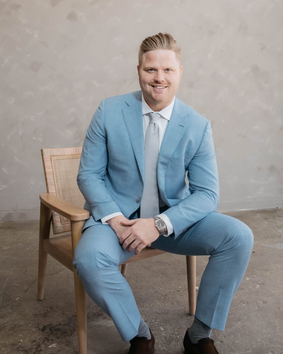 A professional in a blue suit sitting on a chair.