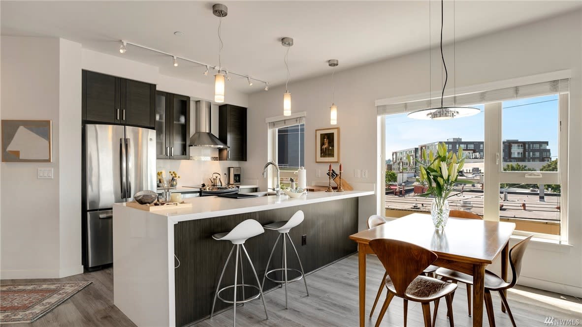 Chic condo dining and kitchen area with stylish decor and city views, illuminated by natural light.