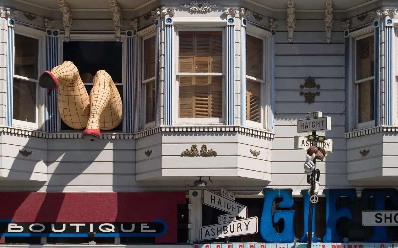 Photo taken in the famous flower Power Street of San Francisco showing oversized legs of a woman coming out of a window