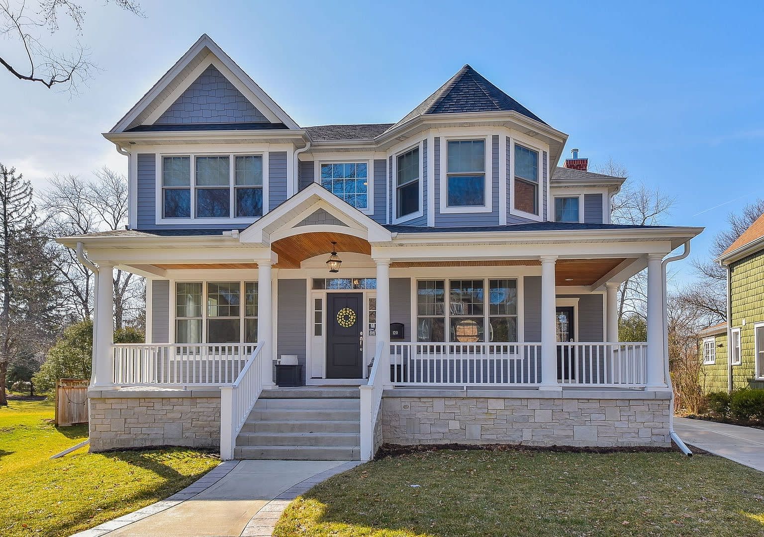 Large, two-story blue and white house with a front porch.