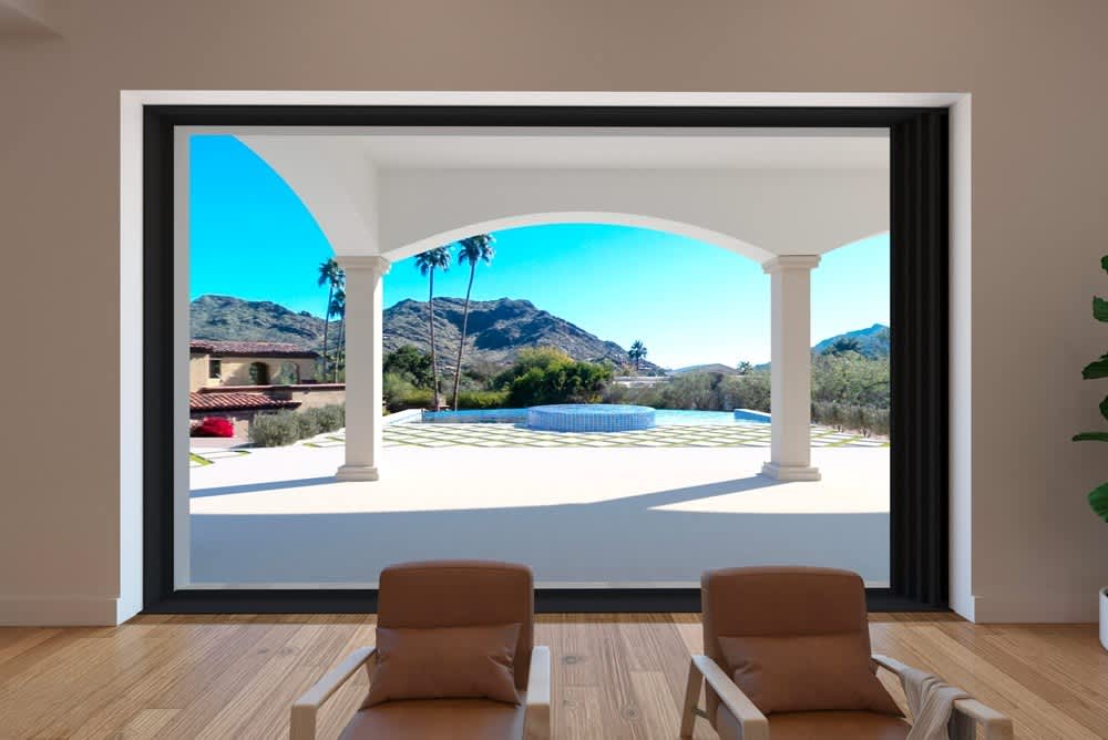 Scenic view of mountains and a fountain from inside a home, framed by large glass doors and arches.