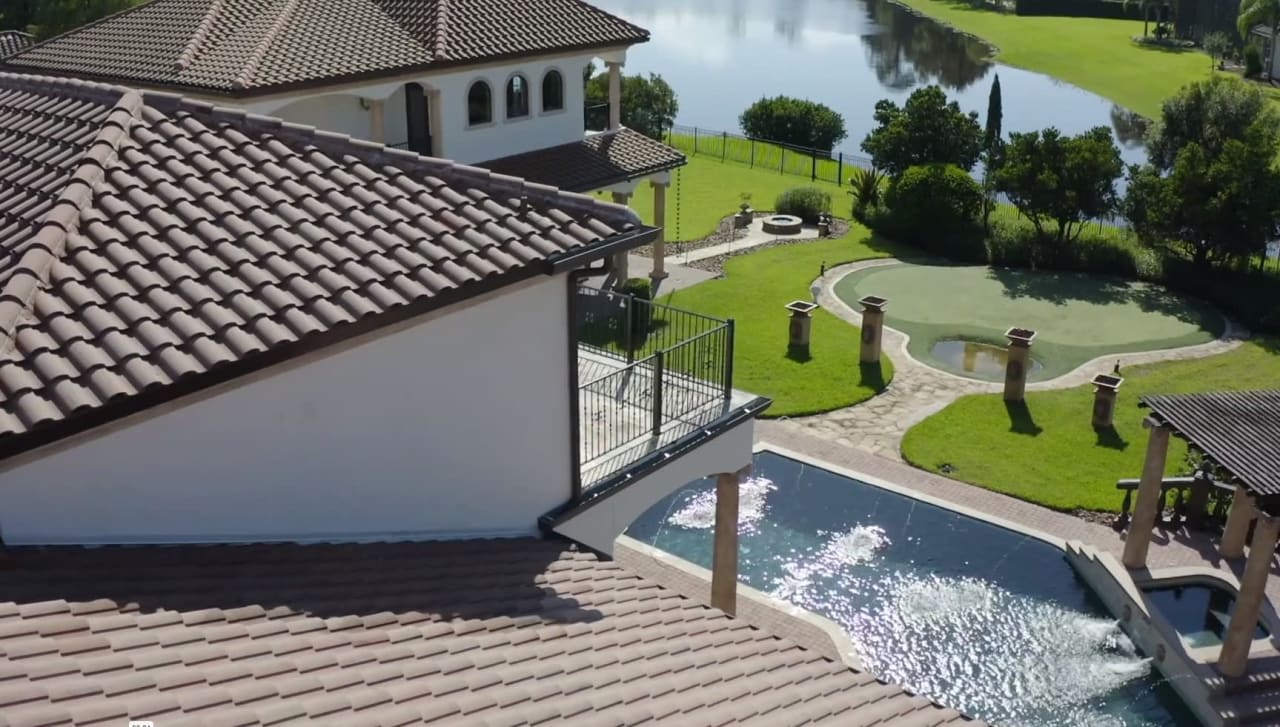 A breathtaking rooftop view of a luxury estate with a sparkling pool and serene lake.