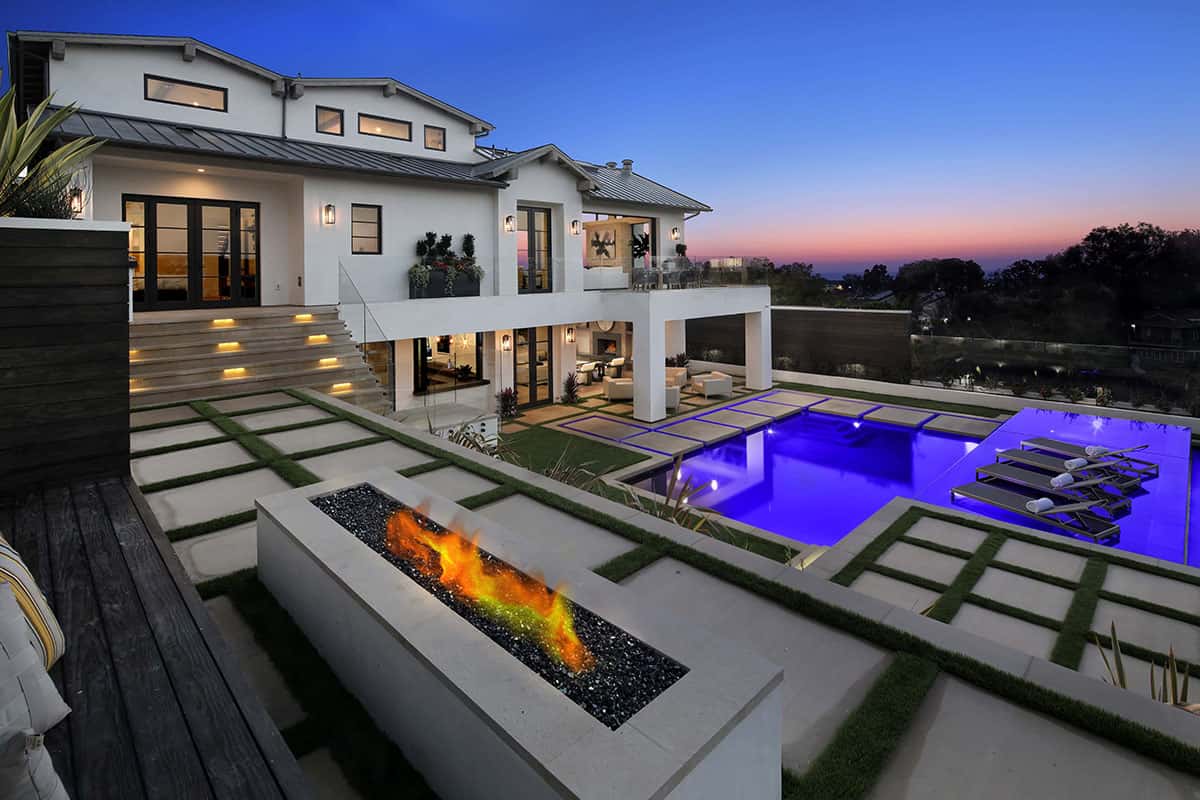 NIght shot of luxury home backyard with pool, fire pit, and gorgeous views.