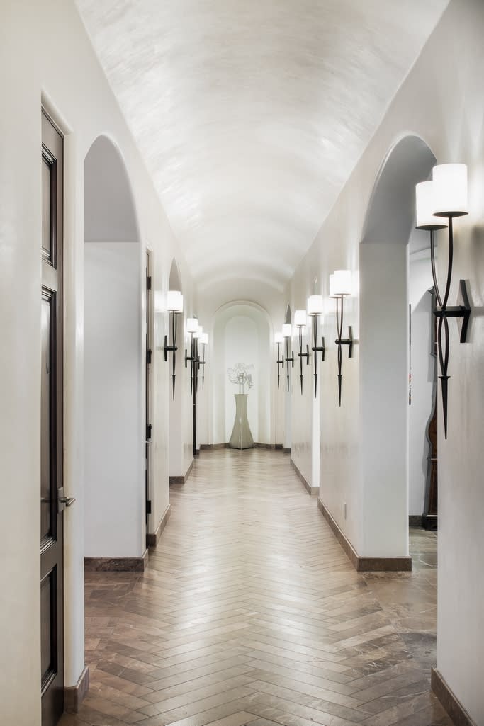 A long hallway with herringbone tile floor and arched doorways.