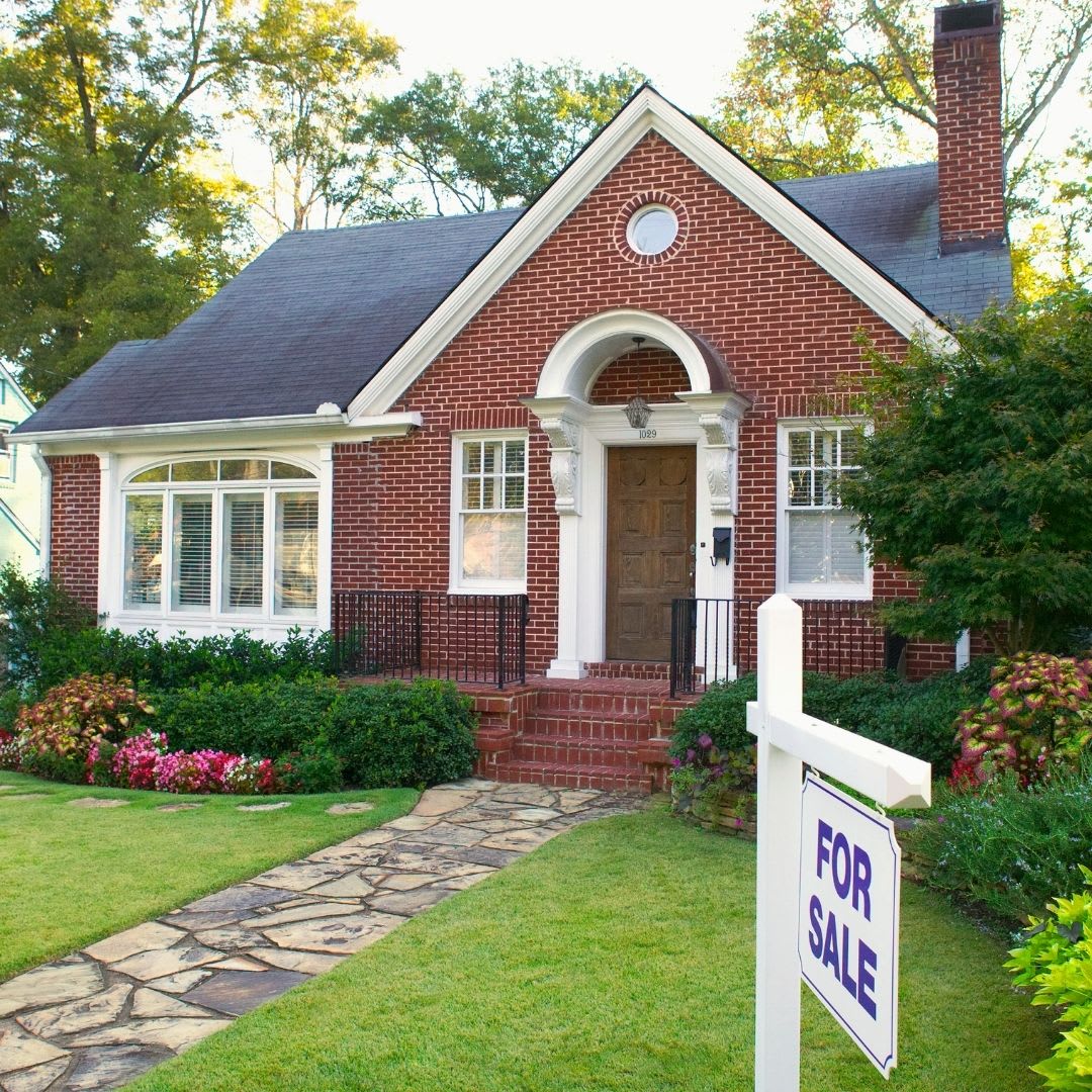 small brick home with a white for sale sign