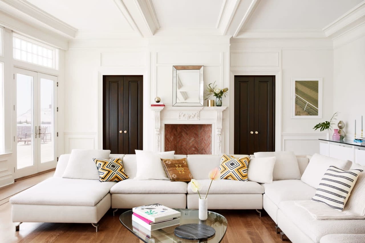 Luxury living room showcasing a coffered ceiling, symmetrical dark panel doors, an ornate white fireplace mantel, wainscoting, and a modern glass coffee table.