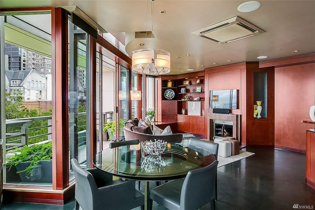 Elegant dining and living space in a high-end condo featuring a fireplace and panoramic views for luxurious comfort.