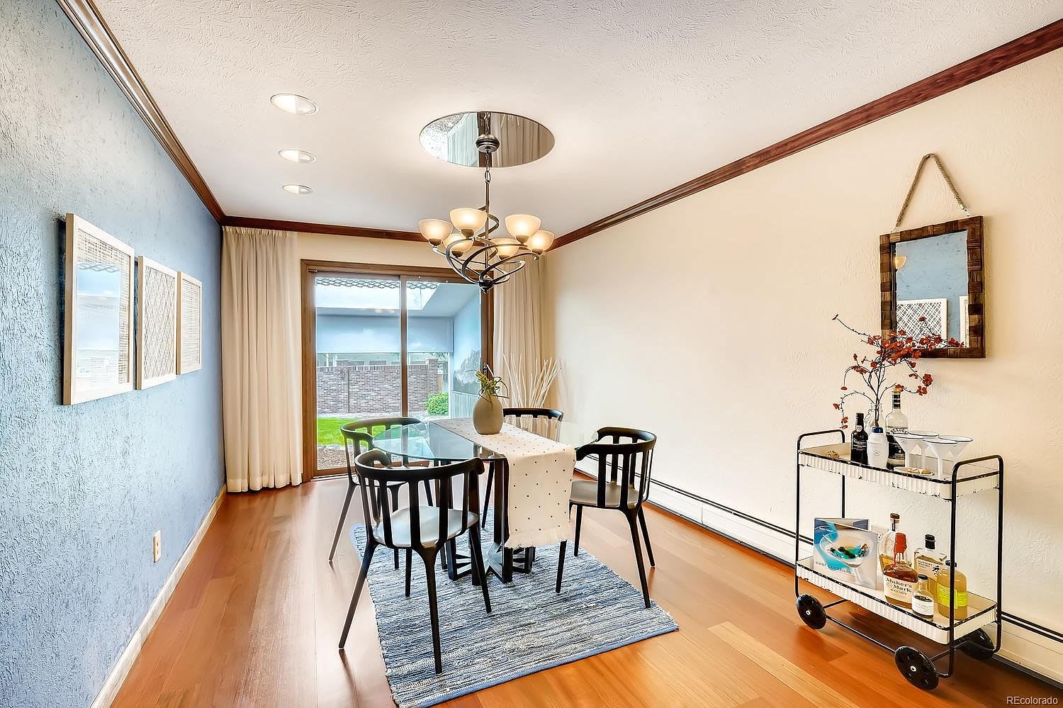 Dining room with a glass-top table, blue accent wall, and sliding doors to a fenced yard.