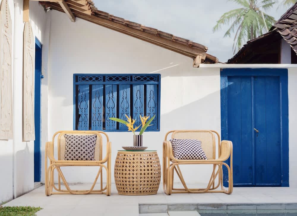 Patio with woven rattan seating, vivid blue doors, and a pool edge.
