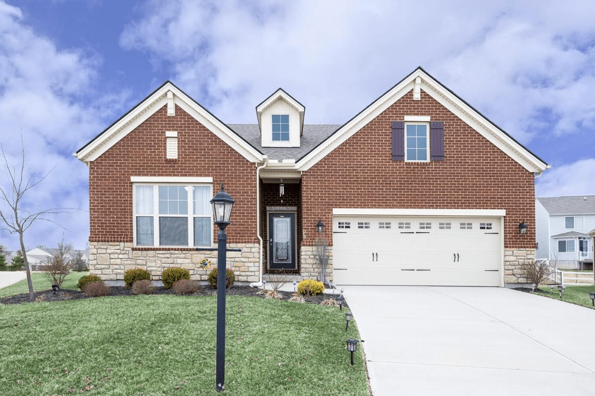 Red brick house with white garage door, black mailbox, and concrete driveway.