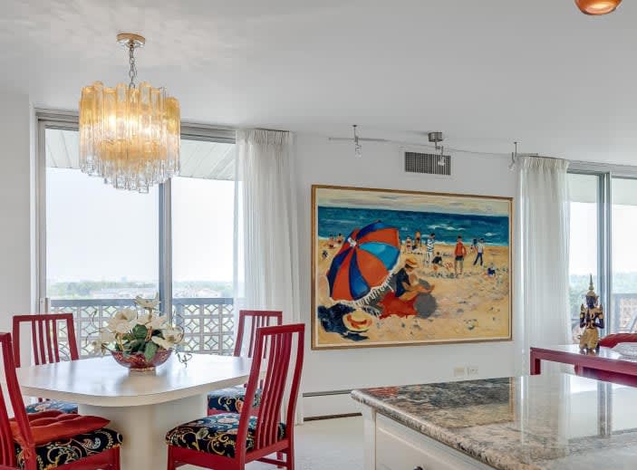 A dining room with a white table and four red chairs