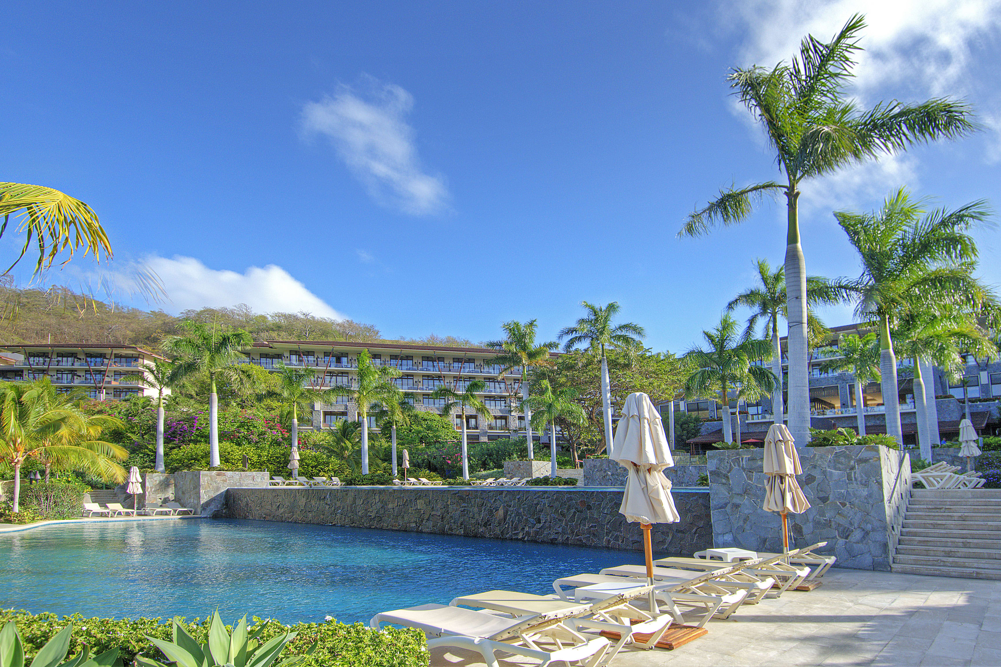 close-up view of dreams las mareas resort pool, with lounge chairs in the foreground and the resort buildings in the background