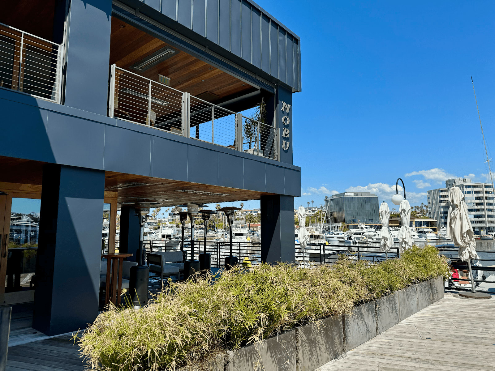 Nobu restaurant exterior near a marina in Newport Beach, with outdoor seating and views of docked boats.