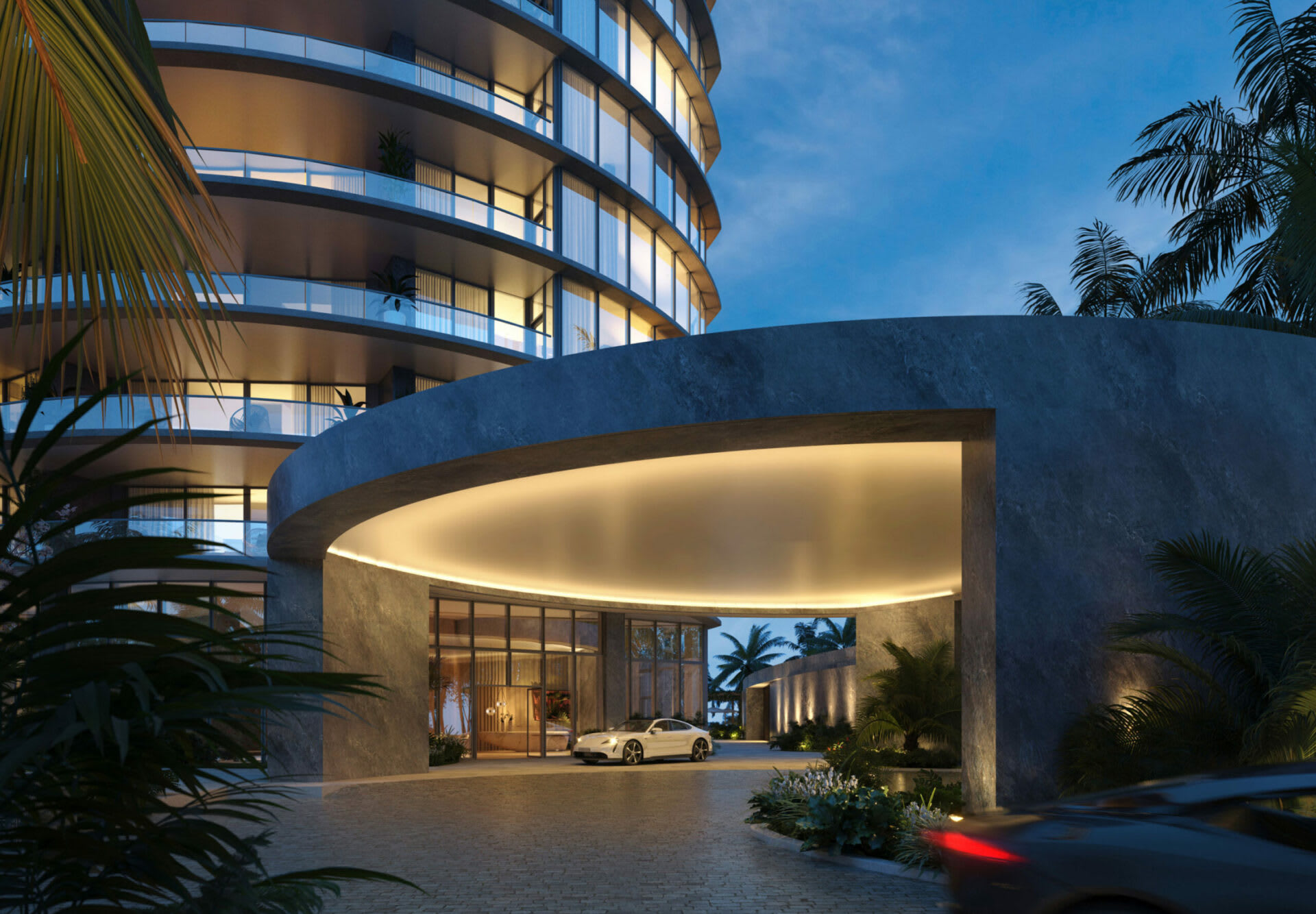 Rivage Bal Harbour’s curved tower and illuminated entrance canopy framed by tropical palms at dusk.